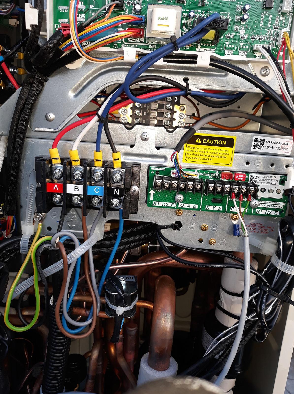 Rozdzielnica elektryczna z przewodami oznaczonymi A, B, C i N, podłączonymi do złączy. Widoczne kable i elementy elektroniczne na płycie głównej urządzenia.