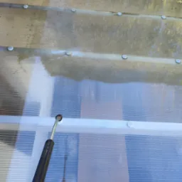 Czyszczenie poliwęglanowego zadaszenia myjką ciśnieniową. Widoczna różnica między umytą a zabrudzoną powierzchnią. Metalowa lanca w dolnej części kadru.