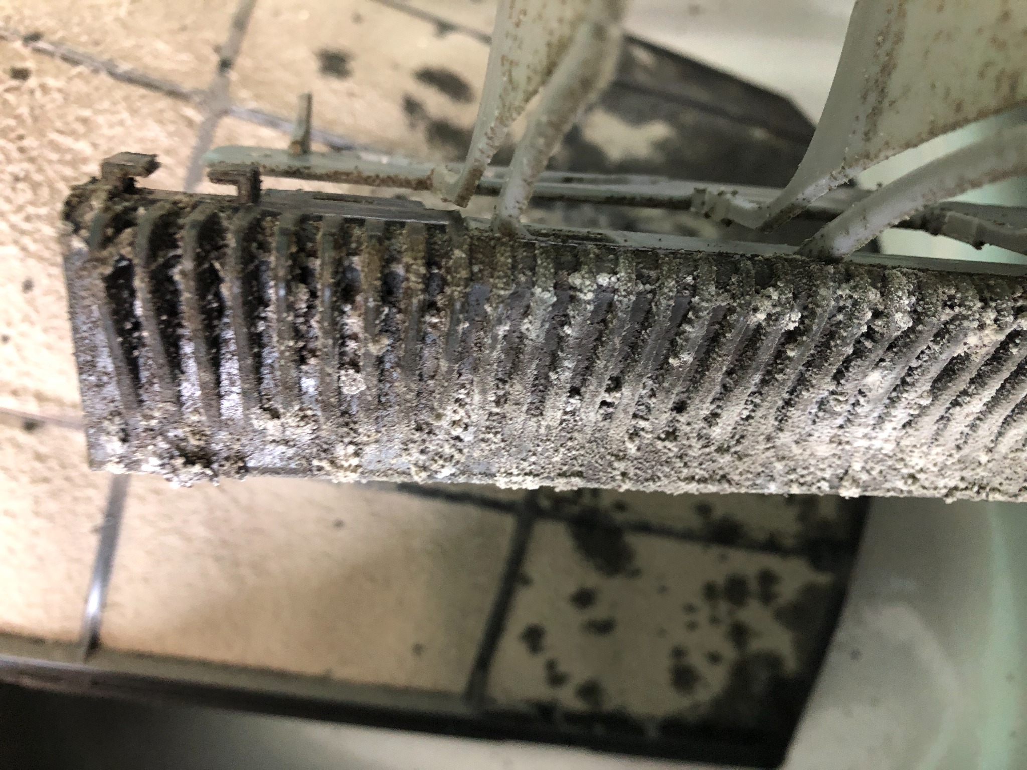 Zanieczyszczony filtr klimatyzacji z widocznym nagromadzeniem kurzu i pleśni na lamelach, ukazujący potrzebę regularnego czyszczenia i serwisu.