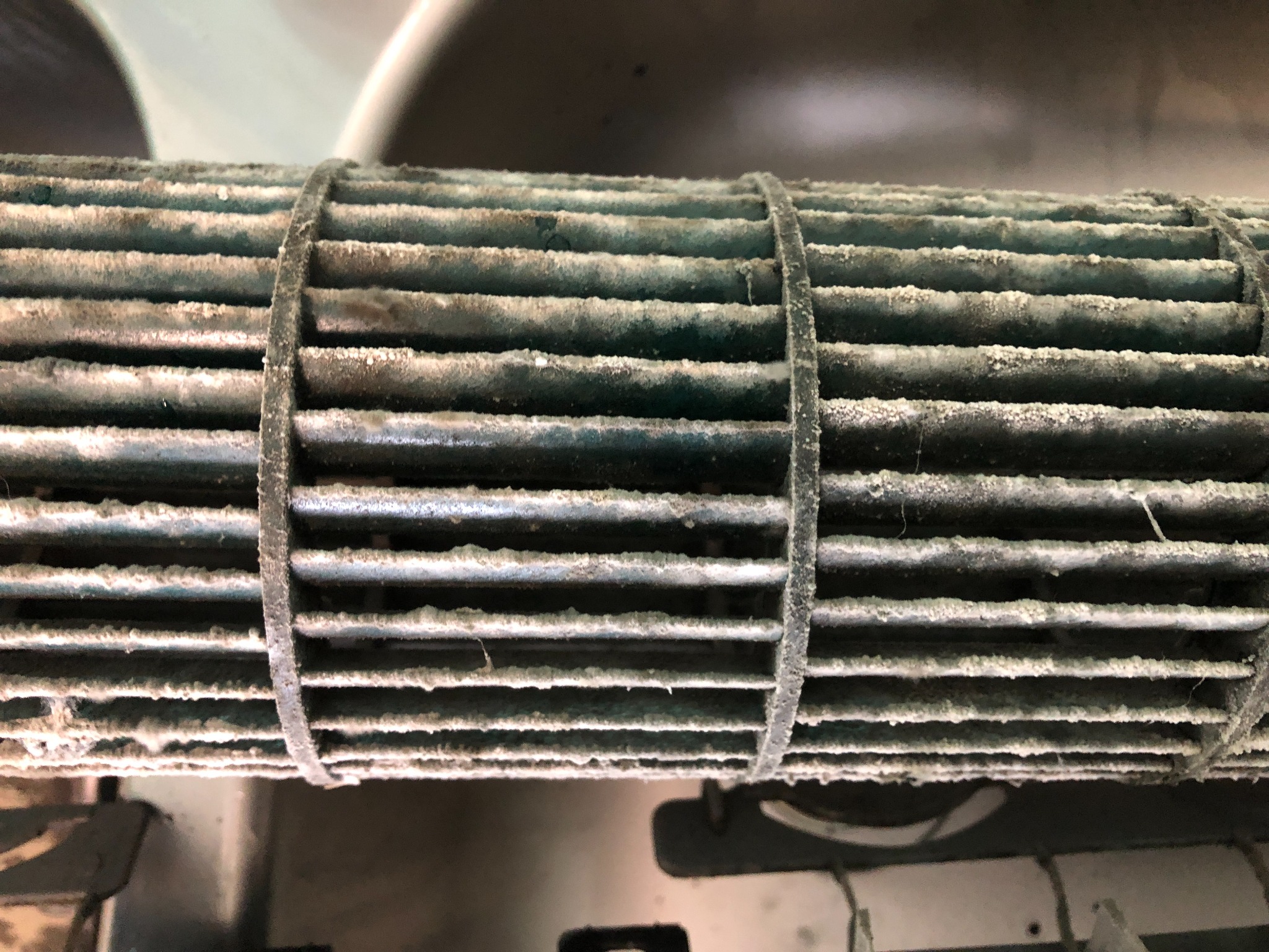 Zabrudzony, poziomy filtr wentylacyjny z lamelami, spięty trzema opaskami. Widoczne osady kurzu i zanieczyszczeń na powierzchni filtra i opasek.