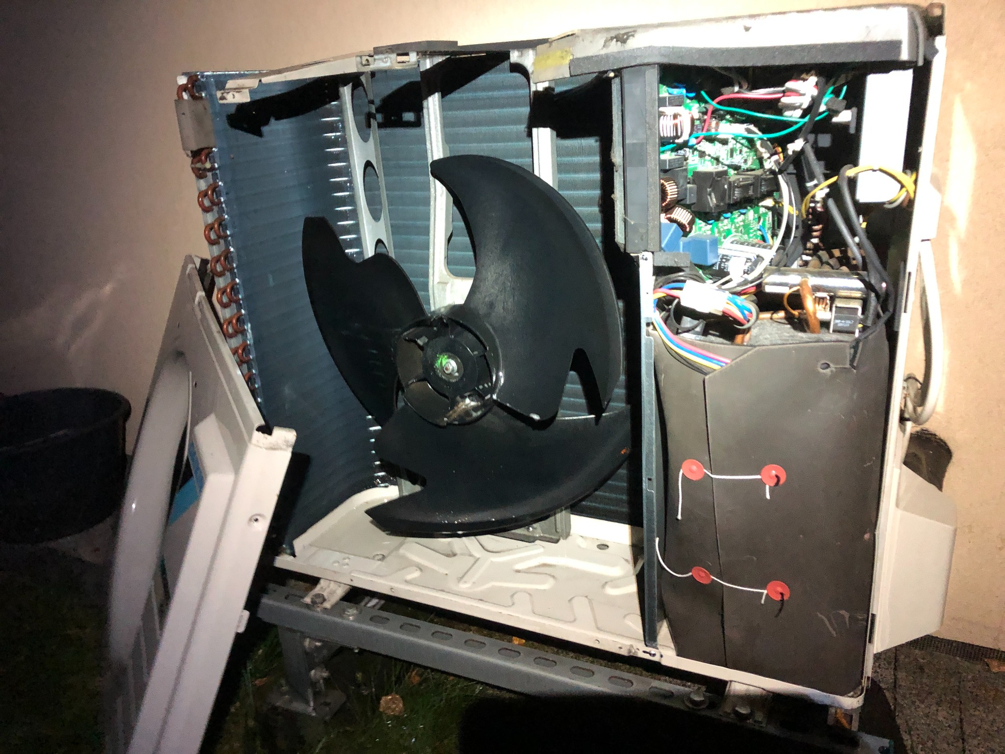 Otwarta obudowa klimatyzatora z widocznym wentylatorem i elektroniką. Panel boczny zdjęty, widoczne elementy wewnętrzne urządzenia. Przegląd techniczny w trakcie.