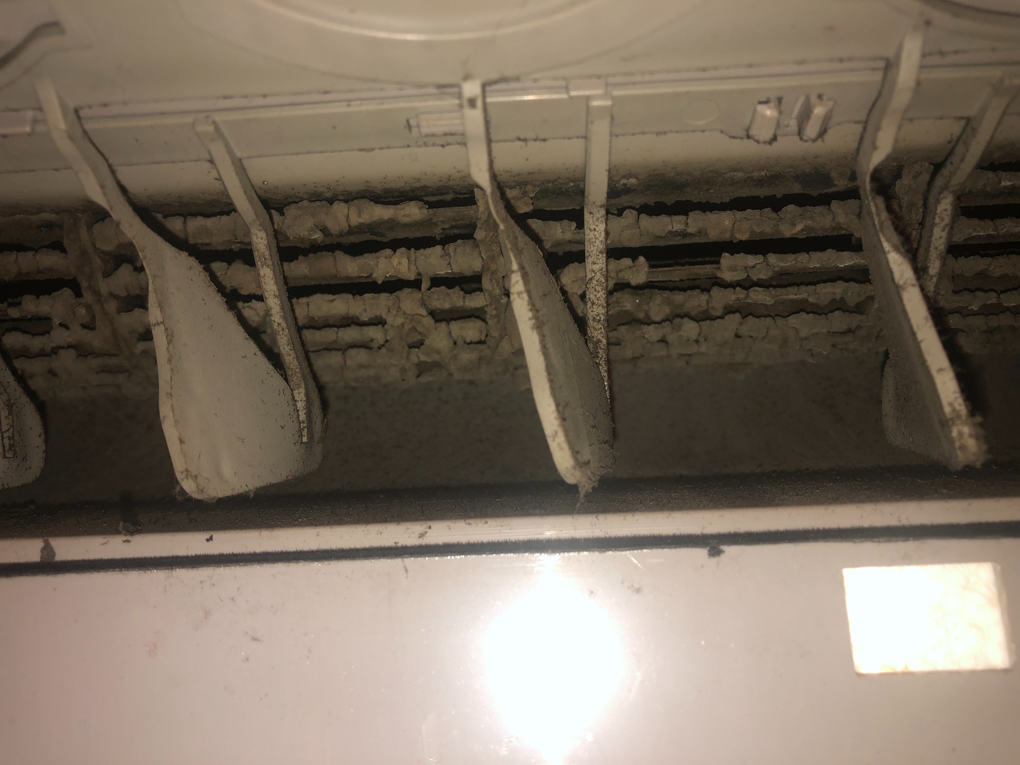 Zanieczyszczone, zakurzone wnętrze klimatyzacji z widocznymi lamelami i filtrami wymagającymi czyszczenia. Brak dbałości o higienę.