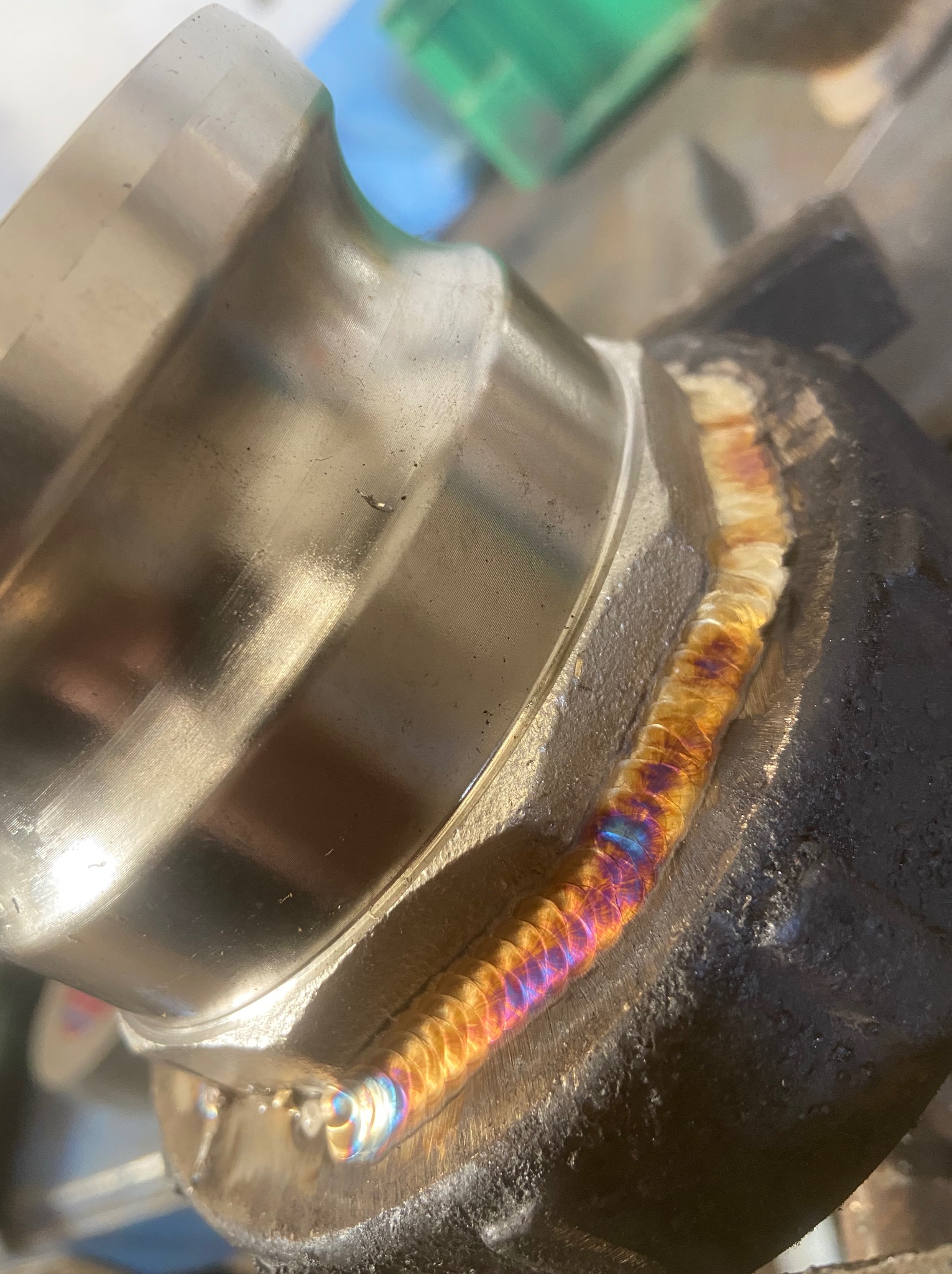 Precyzyjne, kolorowe spawy łączące dwa metalowe elementy. Widoczne detale spoiny, świadczące o wysokiej jakości wykonania i doświadczeniu spawacza.