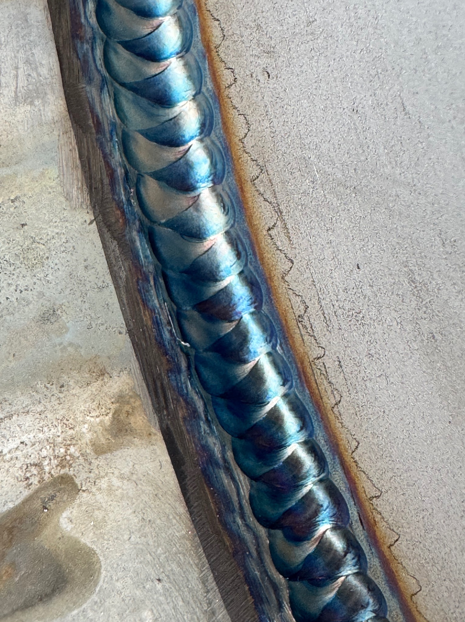 Precyzyjne spoiwo spawalnicze na metalu, z widocznymi detalami i charakterystycznym zabarwieniem termicznym, wykonane z dbałością o estetykę i trwałość.