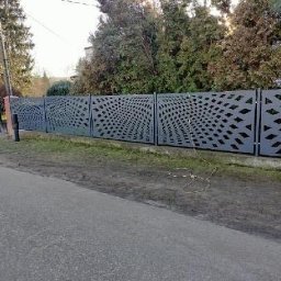 Profesjonalne cięcie CNC - Nowoczesne ogrodzenie panelowe z geometrycznym wzorem, szare panele z wycinanymi rombami, widok z perspektywy ulicy, zieleń w tle.