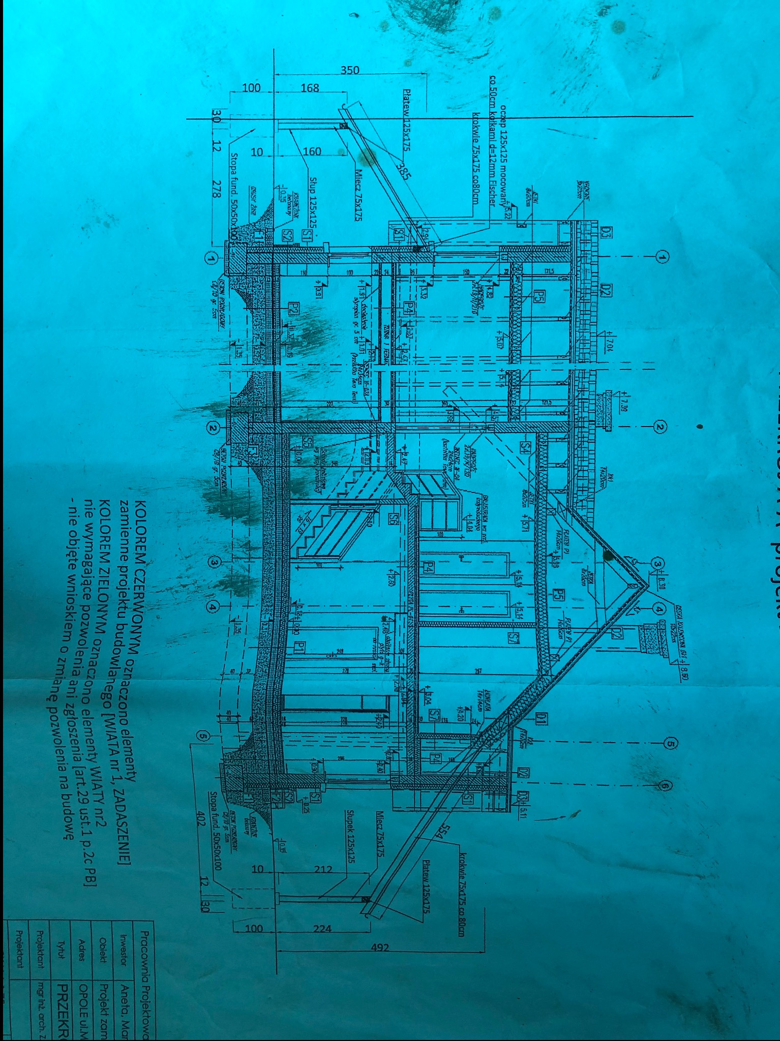 Techniczny rysunek przekroju budynku z detalami konstrukcyjnymi, wymiarami i opisami. Kolorowe oznaczenia elementów konstrukcyjnych.