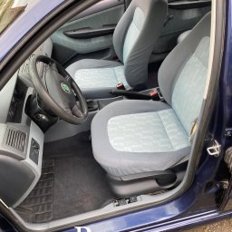 NoVel Clean - Wnętrze auta po czyszczeniu tapicerki. Jasne fotele z delikatnym wzorem, widoczna kierownica i deska rozdzielcza. Czyste dywaniki i odświeżony wygląd wnętrza.