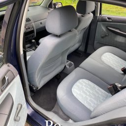 NoVel Clean - Wnętrze samochodu po czyszczeniu: jasnoszare fotele z subtelnym wzorem, otwarte drzwi ukazują czystą tapicerkę, widoczne detale wnętrza.