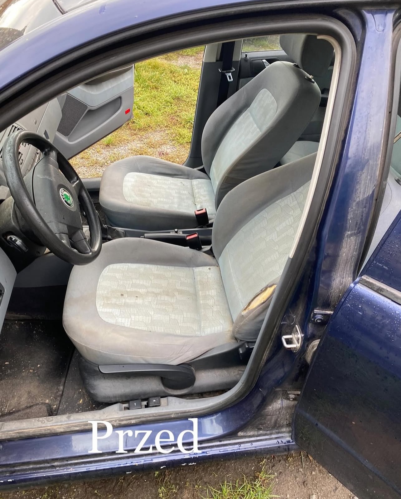 Z bliska wnętrze auta z widocznymi, zabrudzonymi fotelami i otwartymi drzwiami. Na dole kadru widoczny napis 'Przed'.