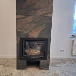 Da-Li HOM BUILDER - Nowoczesny kominek obłożony płytami z kamienia naturalnego o wyraźnym wzorze, dopasowany do marmurowej podłogi. Minimalistyczny design w jasnym wnętrzu.