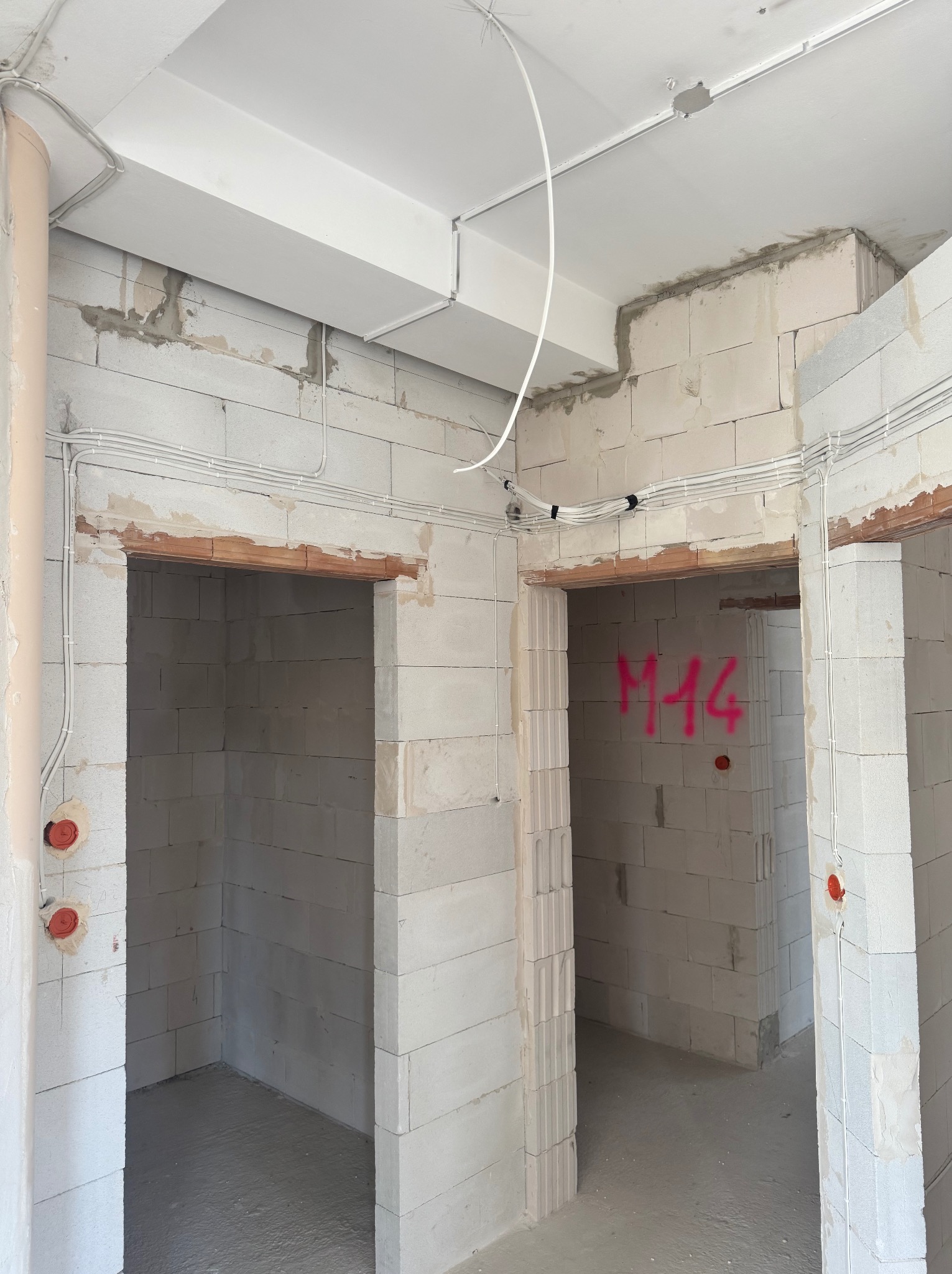 Surowy stan wnętrza z widoczną instalacją elektryczną w Podobinie. Kable prowadzone po ścianach z betonu komórkowego, puszki elektryczne w ścianach.