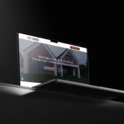 Laptop prezentuje stronę 'Fire & Bricks' z domem z cegły. Kontrastowe oświetlenie, ciemne tło. Widoczne menu strony z zakładkami: O nas, Usługi, Realizacje.