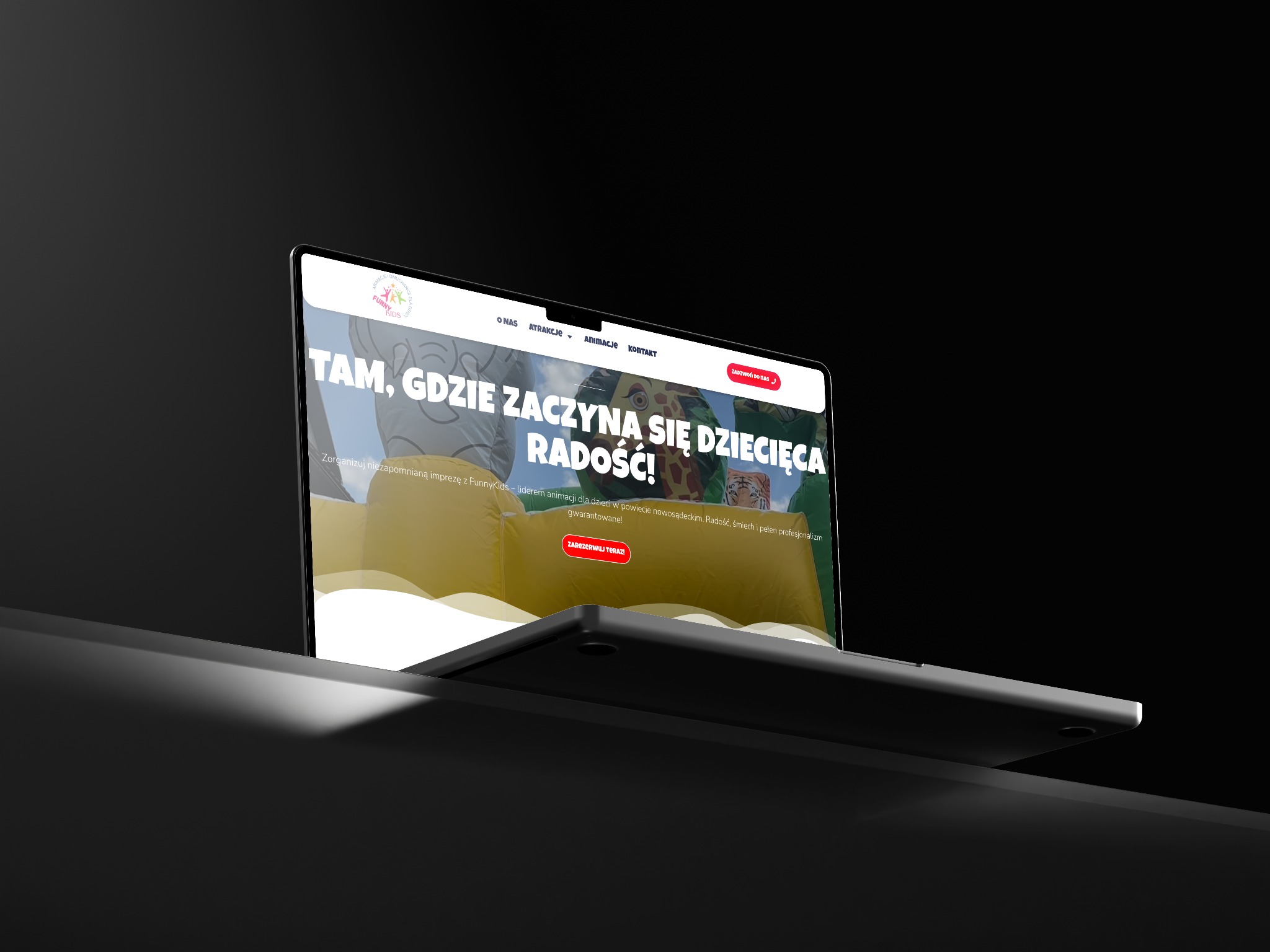Laptop z wyświetloną stroną internetową o tematyce animacji dla dzieci, z hasłem 'Tam, gdzie zaczyna się dziecięca radość!' i przyciskiem 'Zarezerwuj teraz!'.