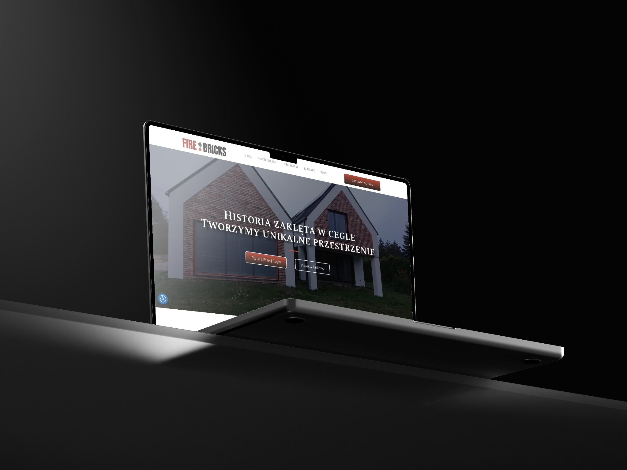 Laptop prezentuje stronę 'Fire & Bricks' z domem z cegły. Kontrastowe oświetlenie, ciemne tło. Widoczne menu strony z zakładkami: O nas, Usługi, Realizacje.