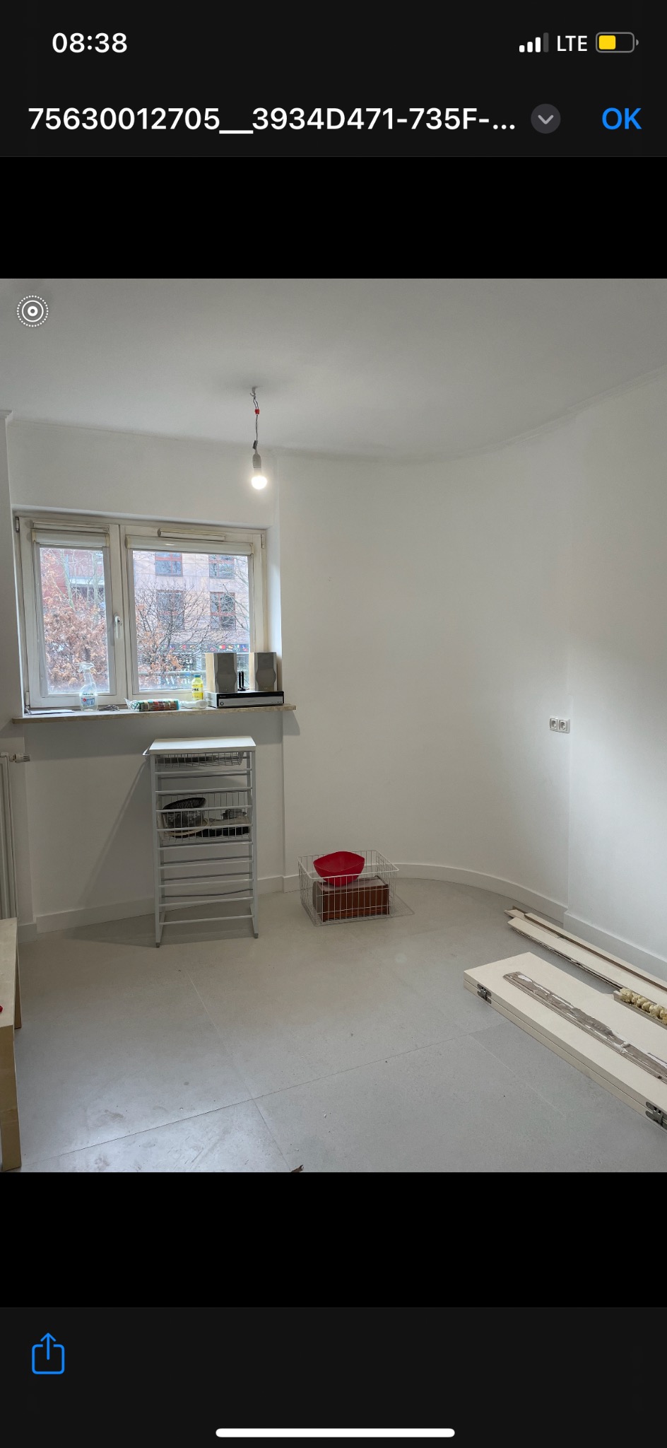 Wnętrze pokoju po malowaniu ścian na biało, widoczne elementy wyposażenia i fragmenty paneli podłogowych. Minimalistyczny wystrój, surowe wykończenie.