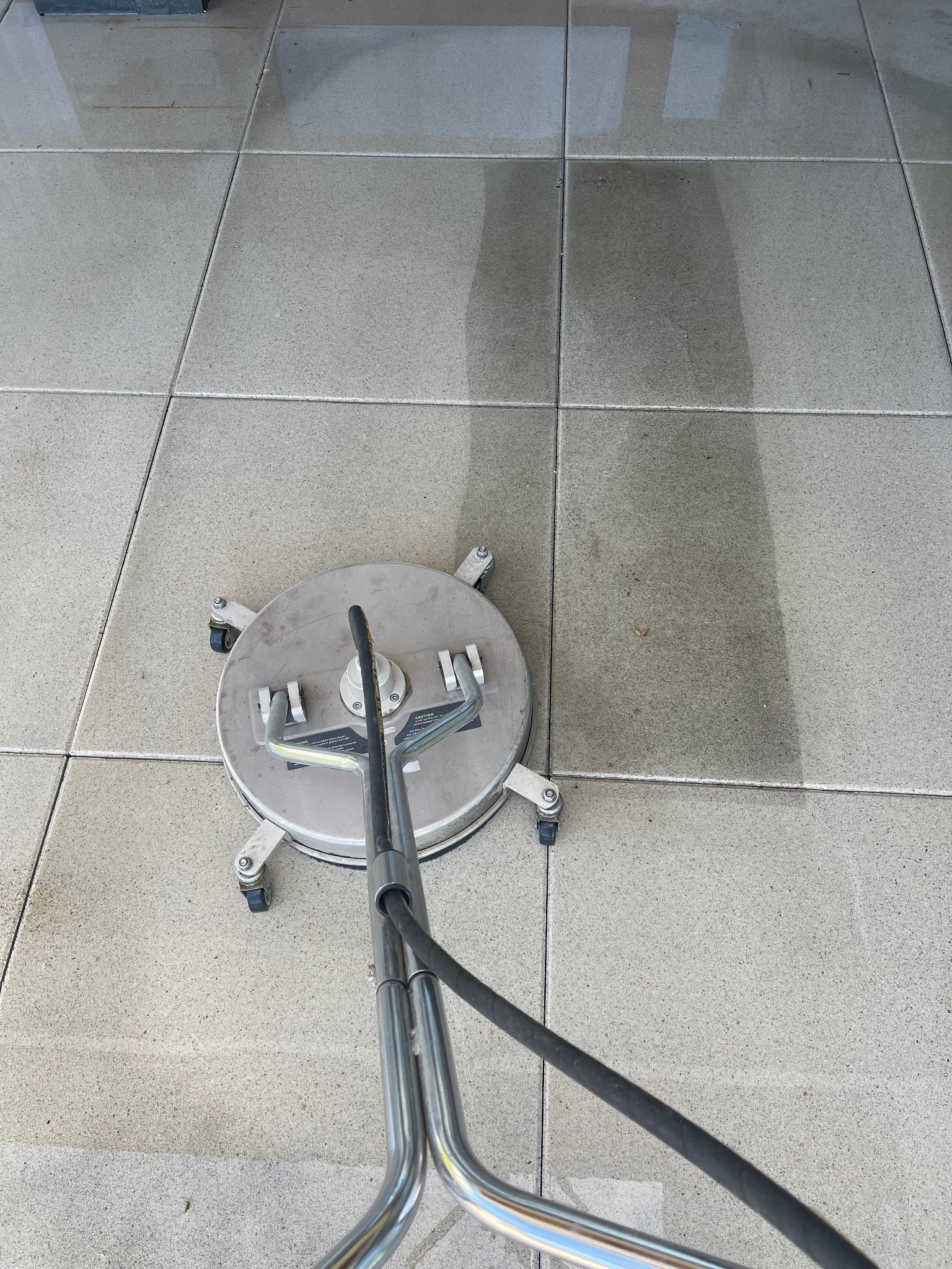 Czyszczenie kostki brukowej za pomocą myjki ciśnieniowej z okrągłą dyszą. Widoczny efekt czyszczenia - różnica między umytą a brudną powierzchnią.