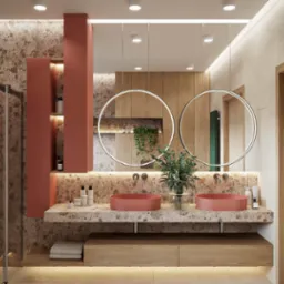 Nowoczesna łazienka z dwoma okrągłymi lustrami, umywalkami w kolorze terakoty i blatem z kamienia. Ściany wykończone płytkami imitującymi kamień, drewniane akcenty.