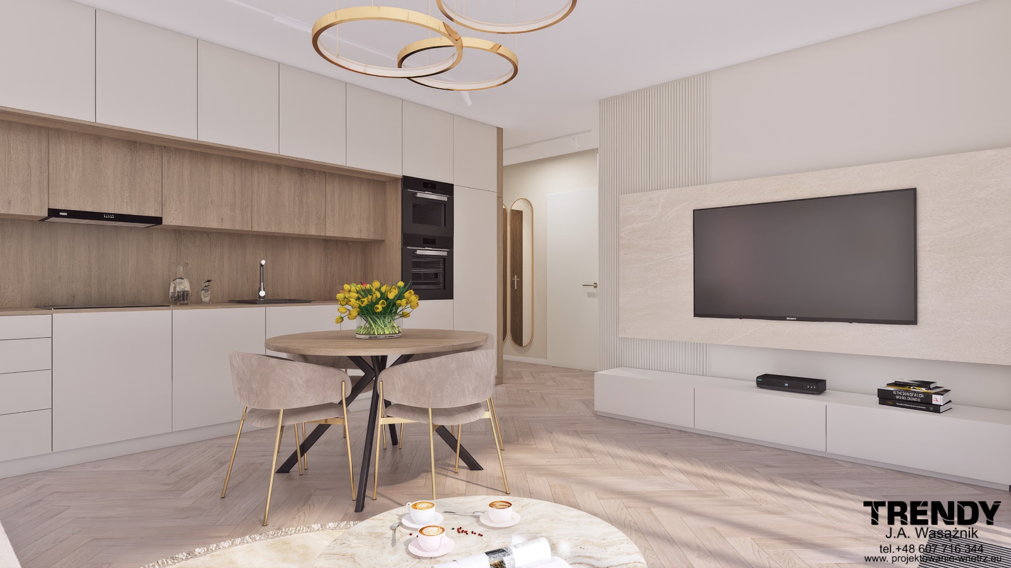 Wnętrze mieszkania w jasnych barwach z drewnianymi akcentami. Widoczna kuchnia z okrągłym stołem i krzesłami oraz ściana z telewizorem. Oświetlenie sufitowe w kształcie okręgów.