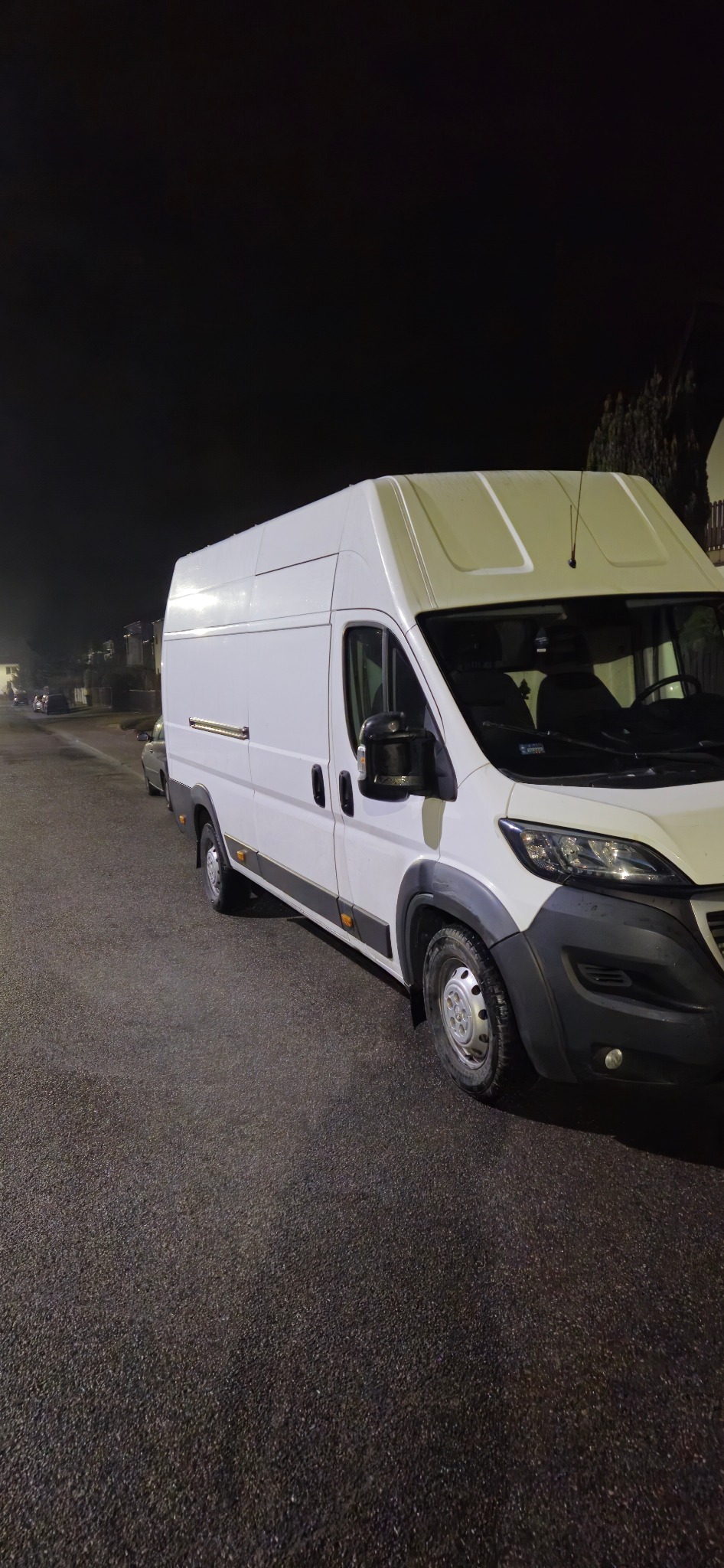 Biały, wysoki furgon dostawczy na ulicy nocą w Rzeszowie. Widoczny z boku, oświetlony światłami ulicznymi, z anteną na dachu.