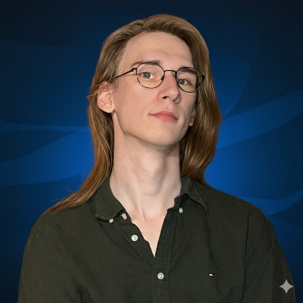 Portret młodego mężczyzny z długimi blond włosami i okularami w metalowych oprawkach, ubrany w ciemnozieloną koszulę na tle ciemnoniebieskiego, wzorzystego tła.