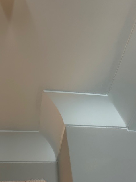 Detal wykończenia wnętrza: białe listwy przysufitowe z zaokrąglonym narożnikiem, precyzyjnie zamontowane na styku ściany i sufitu, tworzące eleganckie przejście.