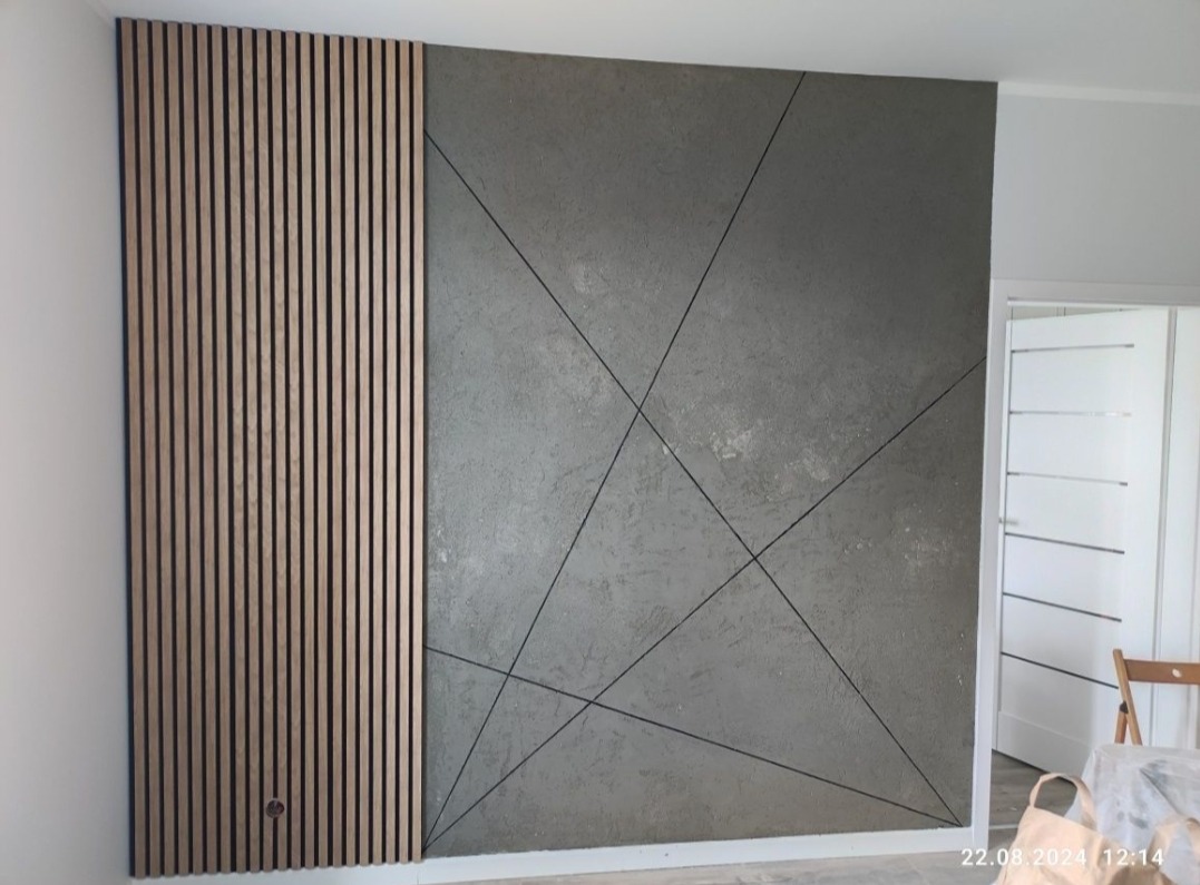 Dekoracyjna ściana z drewnianymi lamelami po lewej i szarą fakturą z geometrycznym wzorem po prawej. Nowoczesny design wnętrza.