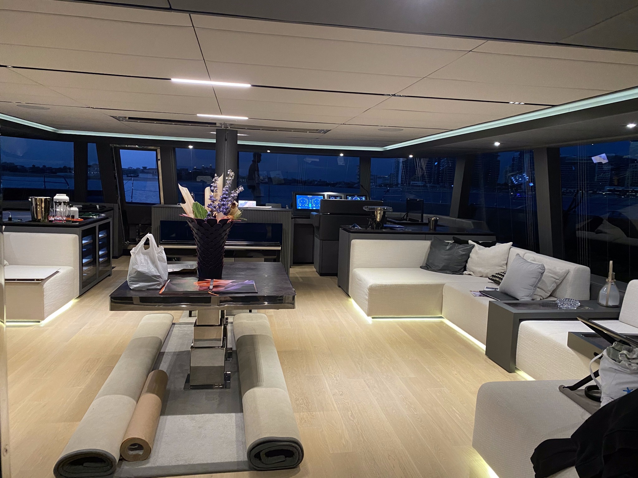 Nowoczesne oświetlenie LED w luksusowym wnętrzu jachtu, z widokiem na nocne miasto przez panoramiczne okna i subtelnym podświetleniem pod meblami.