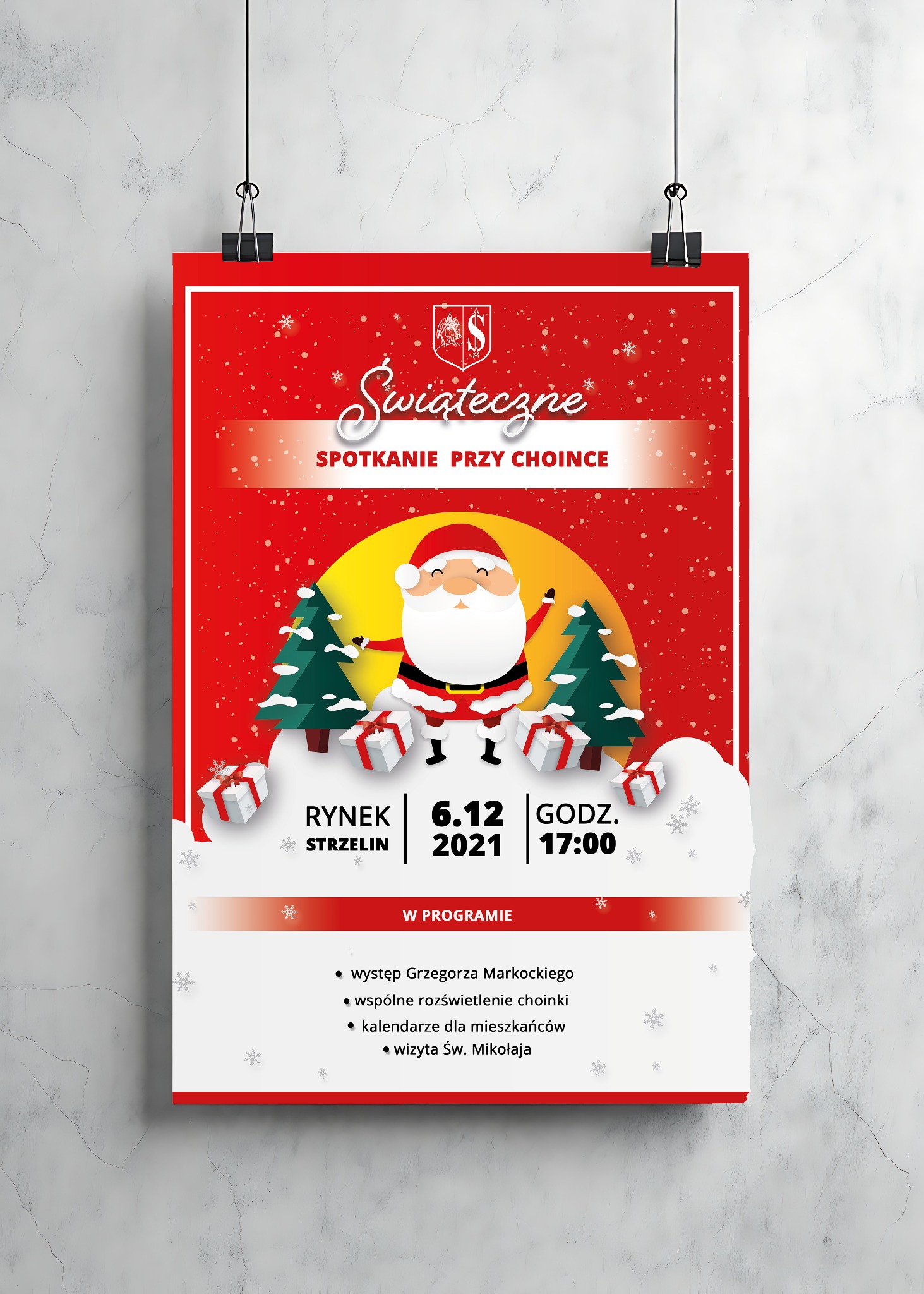Czerwony plakat z grafiką świąteczną, wiszący na ścianie, informujący o spotkaniu przy choince 6.12.2021 w Strzelinie. Grafika przedstawia Świętego Mikołaja i choinki.