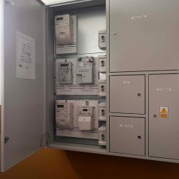 PRO-ELECTRO MATEUSZ BORAWSKI - Otwarta szafa elektryczna z licznikami i bezpiecznikami w Pisz. Widoczne opisy: Tablica Główna, Wlz, GN Serwisowe, Administracja. Instalacje elektryczne.