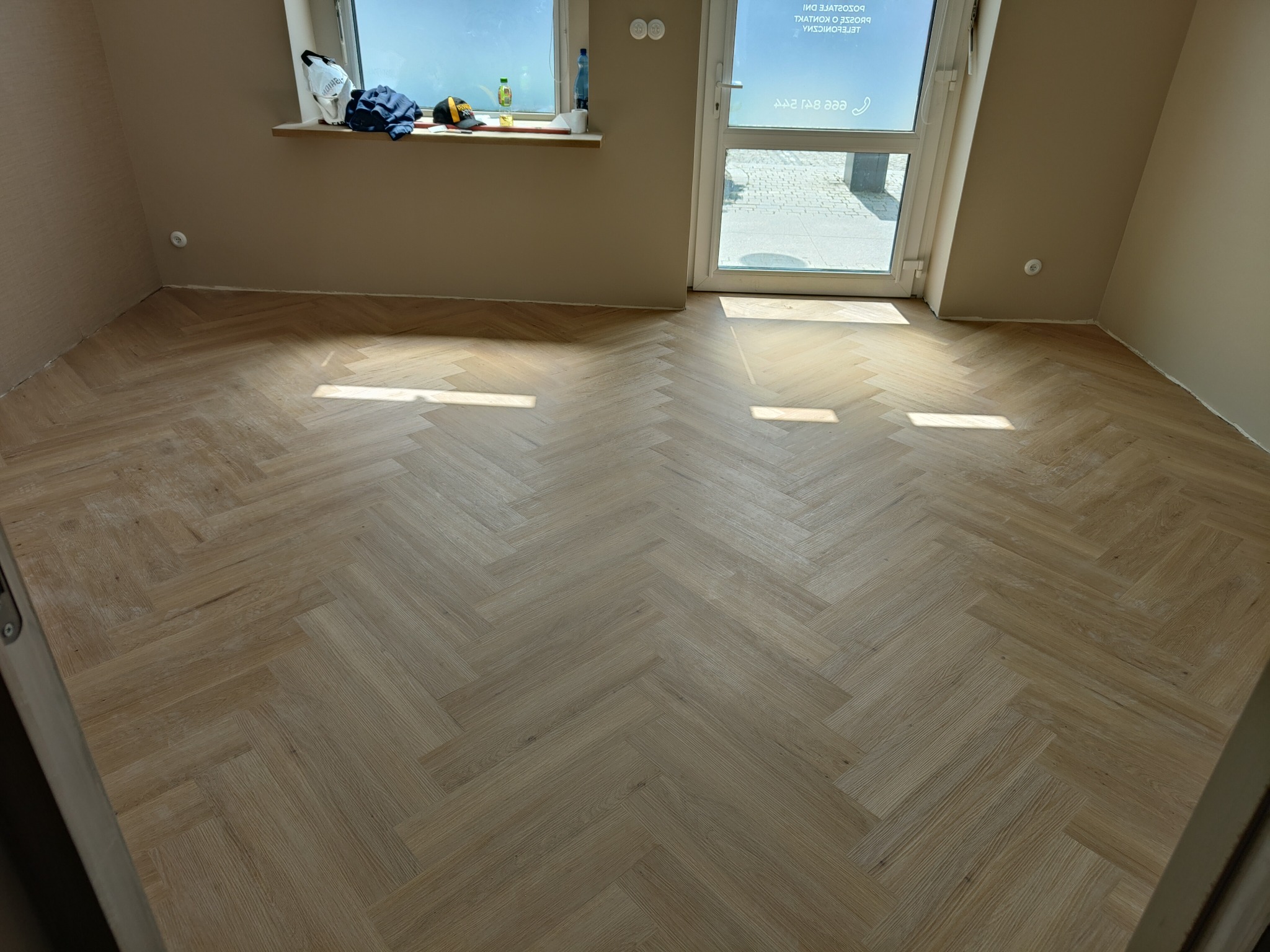 Ułożona podłoga z paneli w jodełkę francuską w jasnym odcieniu drewna, widok z góry, naturalne światło podkreśla wzór. Świeżo wykończone wnętrze.