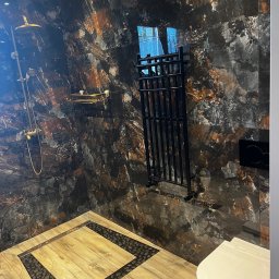 Józef Zubek Z BUD - Nowoczesna łazienka z deszczownicą, grzejnikiem drabinkowym i toaletą. Ściany i podłoga wyłożone płytkami imitującymi marmur i drewno.