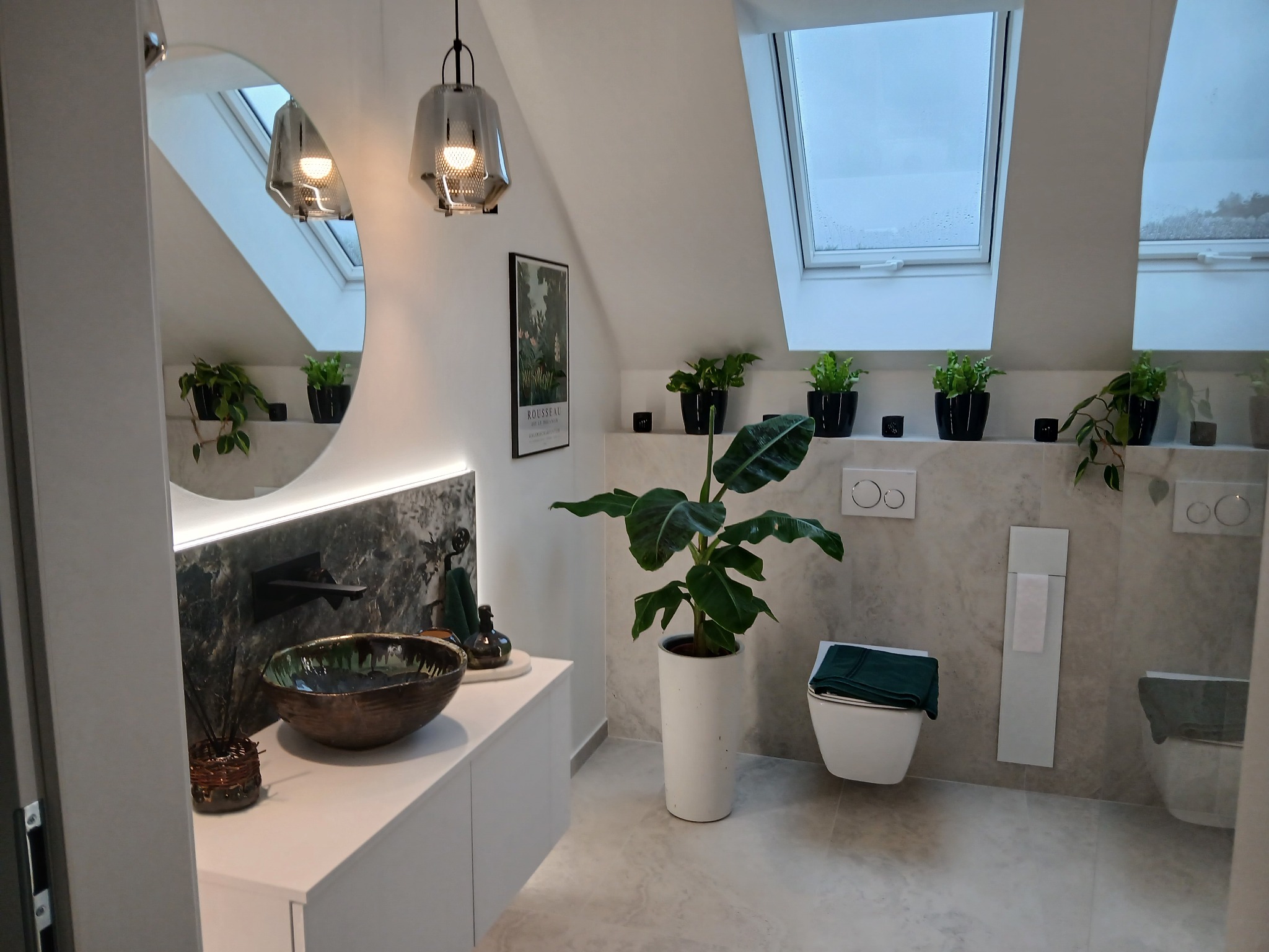 Nowoczesna łazienka na poddaszu z oknami dachowymi, umywalką w stylu boho i roślinami doniczkowymi. Minimalistyczne wykończenie w jasnych kolorach z akcentami zieleni.