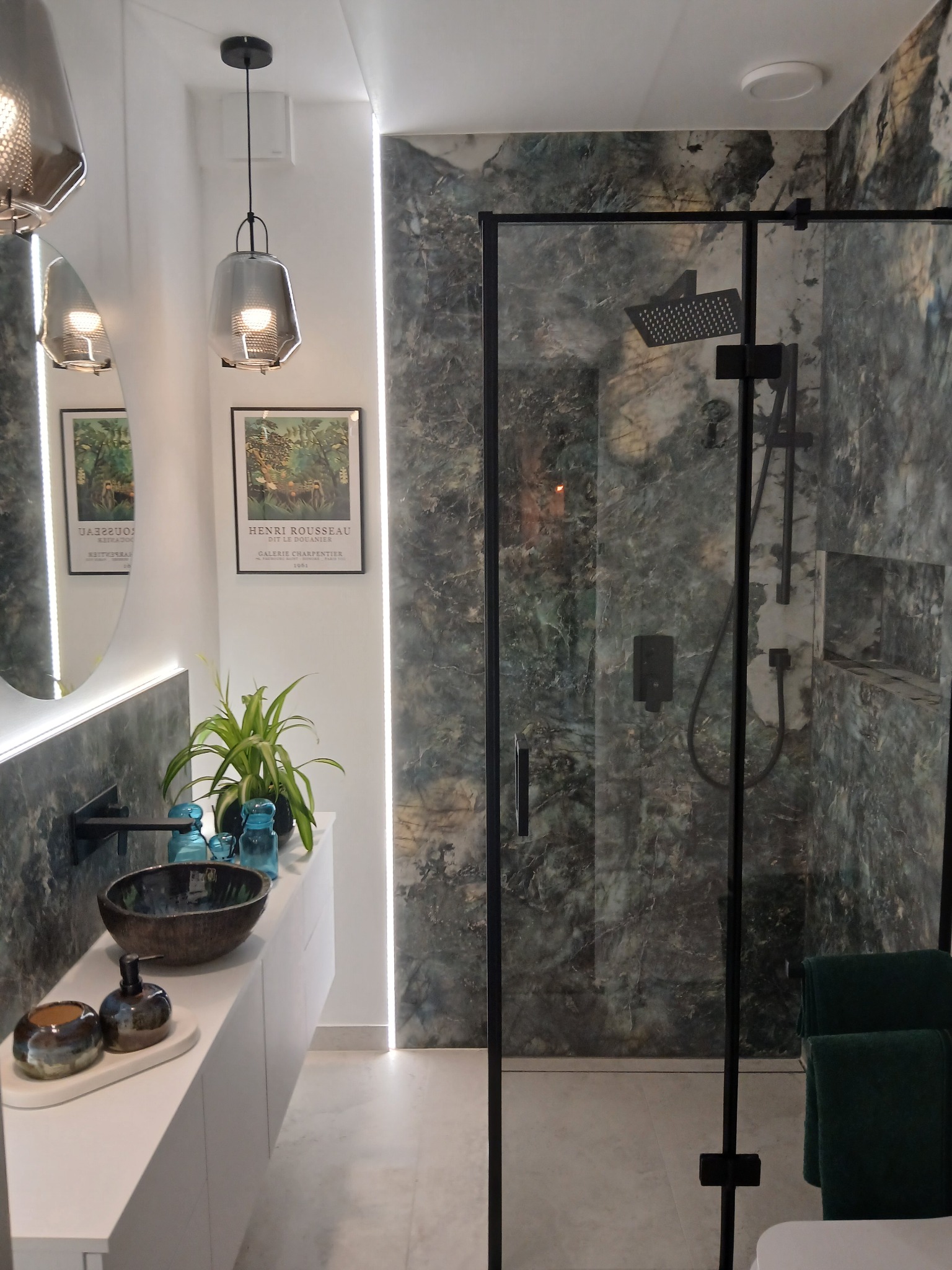 Nowoczesna łazienka z kabiną typu walk-in, umywalką nablatową i dekoracyjnymi lampami wiszącymi. Marmurowe płytki i minimalistyczna armatura w czarnym kolorze.