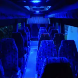 Wnętrze autobusu w Lubartowie z niebieskim oświetleniem LED, widok na fotele z wzorzystą tapicerką. Klimatyczne oświetlenie tworzy unikalny nastrój w pojeździe.