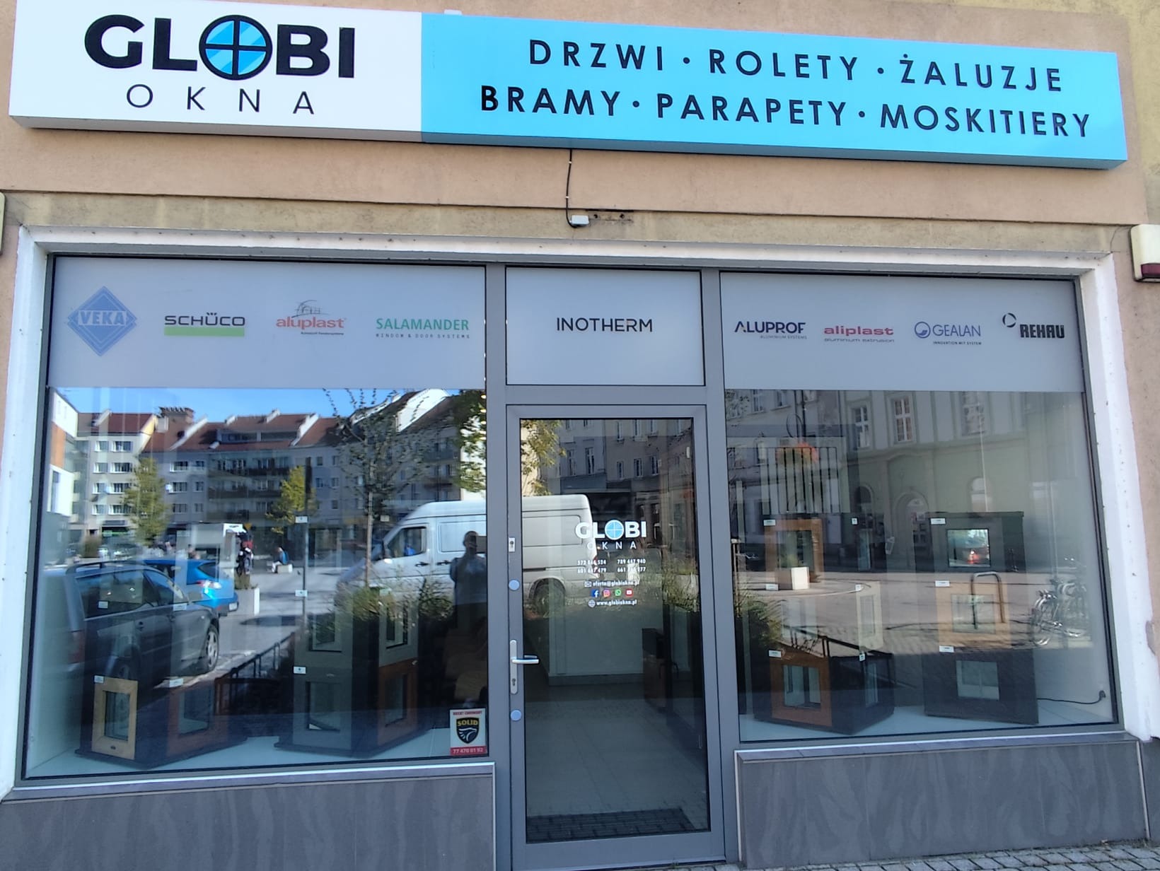 Fasada salonu sprzedaży stolarki okiennej i drzwiowej z logo Globi Okna, prezentującego okna i drzwi różnych marek w witrynie.