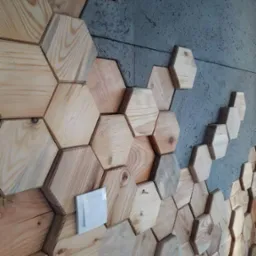 Drewniana ściana z heksagonalnych paneli, surowy beton w tle, włącznik światła wkomponowany w drewnianą mozaikę. Nietypowe wykończenie wnętrza.