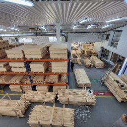 CLIC HOUSE WOOD - Magazyn tarcicy w Kroczycach: liczne stosy obrobionego drewna na regałach i podłodze, przygotowane do dalszej obróbki. Widok z góry na halę produkcyjną.