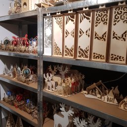 CLIC HOUSE WOOD - Regał z drewnianymi ozdobami: wycinane laserowo renifery, choinki, karoce z bombkami i ażurowe panele, tworzące bożonarodzeniowy asortyment stolarski.