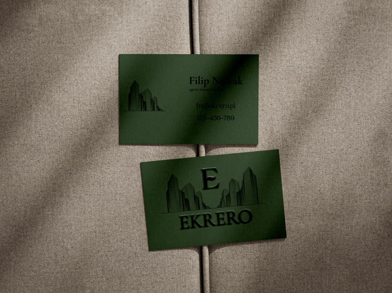 Dwie zielone wizytówki z czarnym nadrukiem na beżowym tle. Górna wizytówka z imieniem i nazwiskiem Filip Nowak, dolna z logo EKREO i motywem budynków.