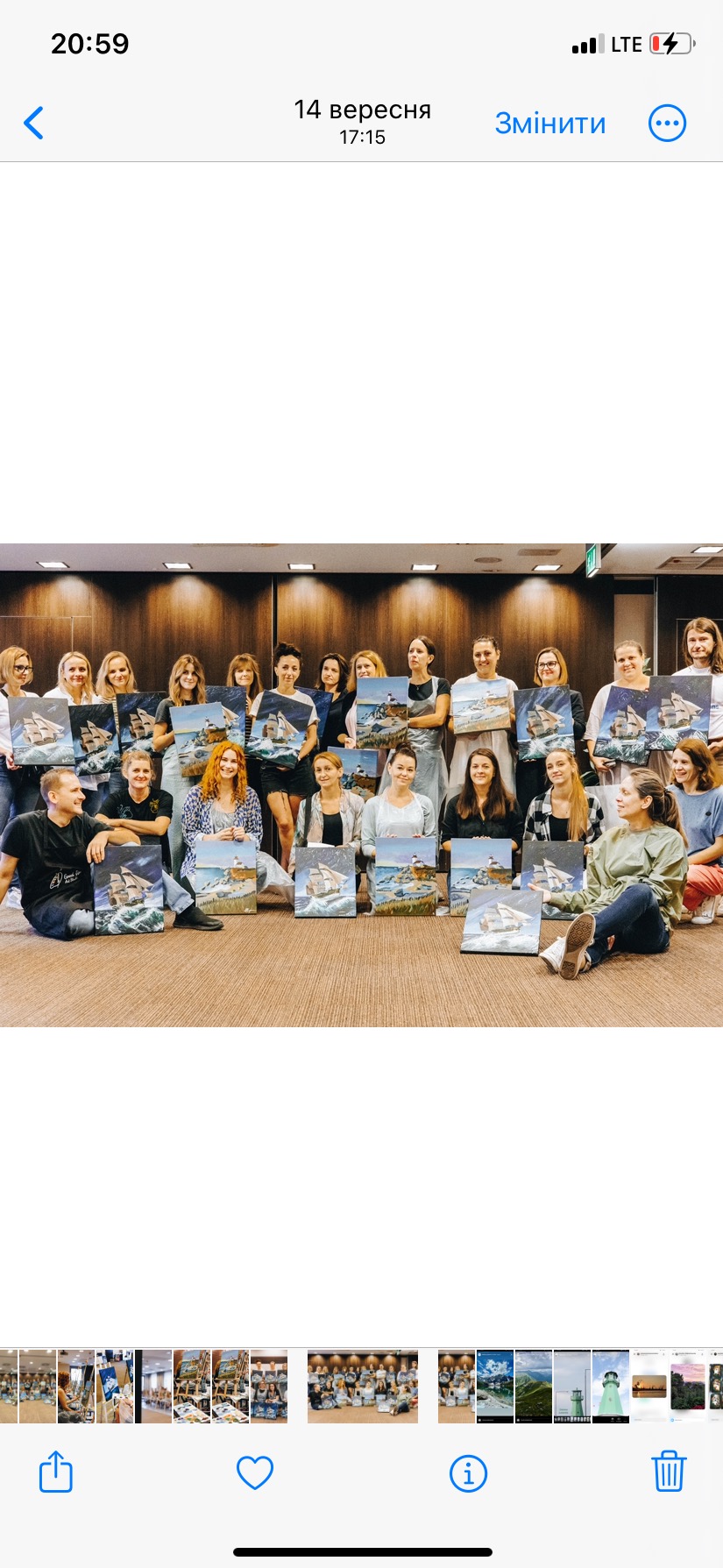 Grupa uśmiechniętych osób prezentuje obrazy z motywem morskim, prawdopodobnie po warsztatach malarskich zorganizowanych przez agencję eventową.