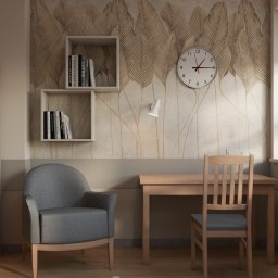 ARCHITEKA TOBIASZ KOCH - Neutralna aranżacja pokoju z biurkiem, szarą sofą i drewnianą szafą. Na ścianie półki z książkami i zegar, a na parapecie doniczkowa roślina.