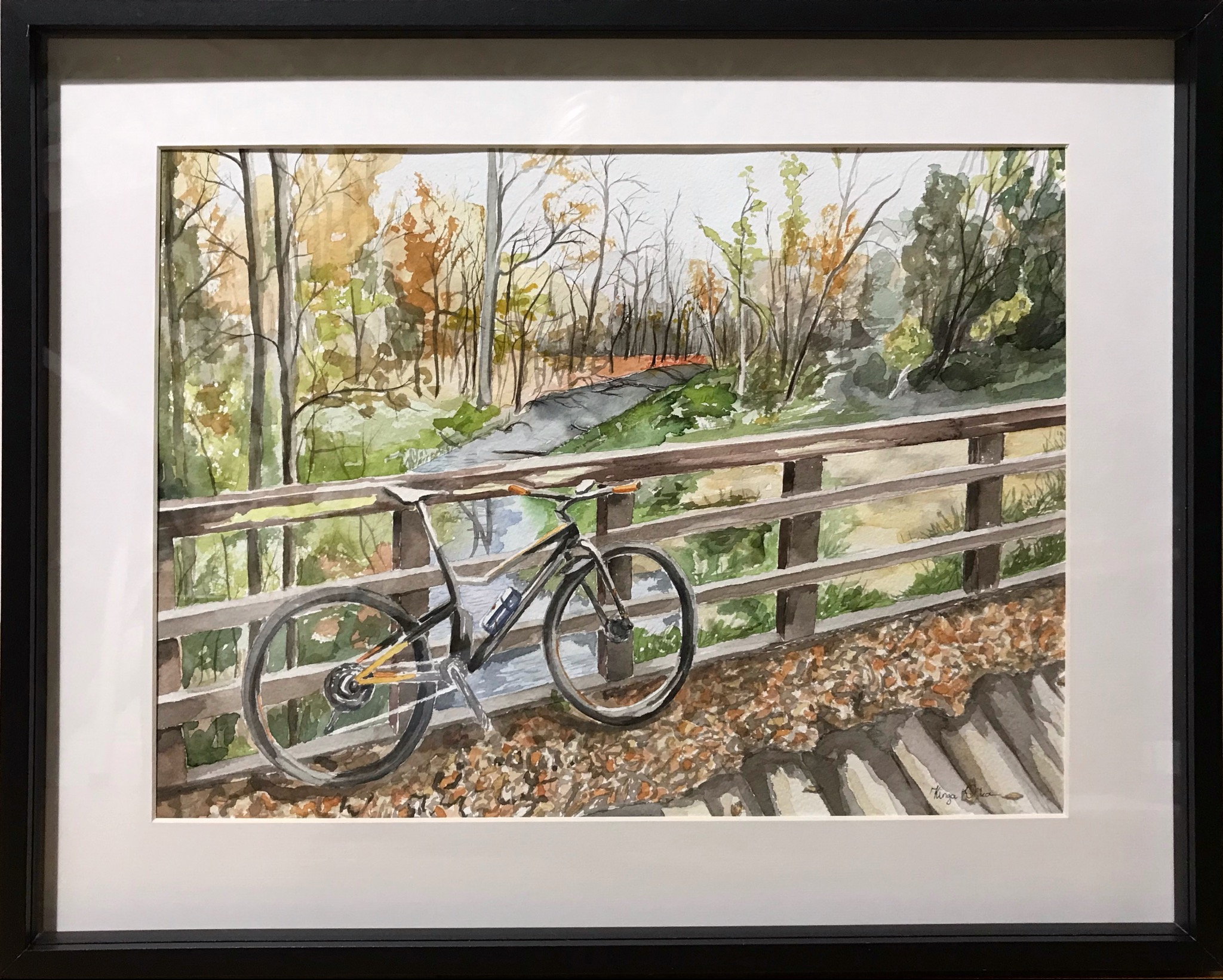 Akwarela w ramie: rower oparty o barierkę mostu, w tle jesienny krajobraz z rzeką. Sygnowany obraz.
