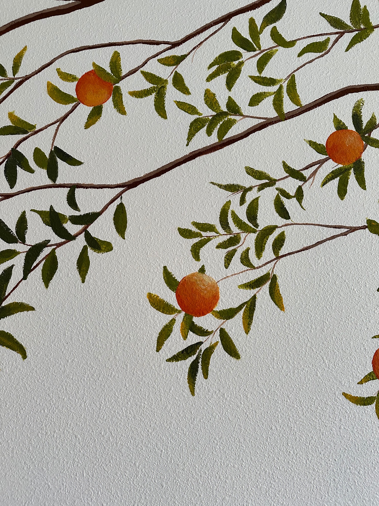 Akrylowe malowidło na ścianie: gałęzie z zielonymi liśćmi i pomarańczowymi owocami na jasnym, teksturowanym tle. Widoczne pociągnięcia pędzla.
