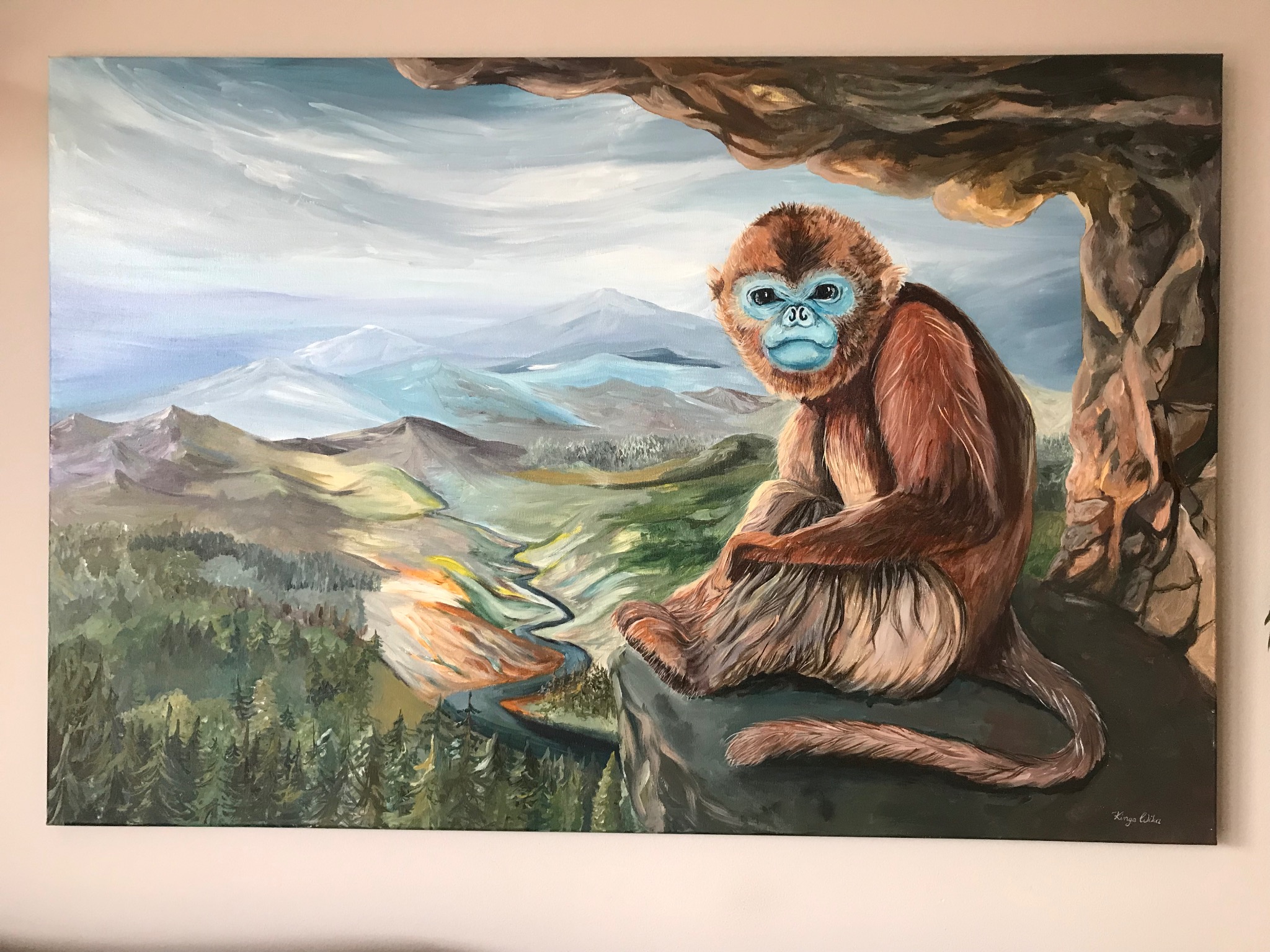 Akrylowy obraz przedstawiający siedzącego, brązowego małpoluda o niebieskiej twarzy na tle górskiego pejzażu z rzeką, namalowany w stylistyce fantasy.