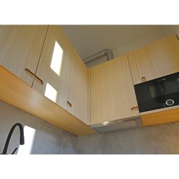 Witold Szostak - Szostak Atelier - Nowoczesna kuchnia: jasne, drewniane szafki górne z oryginalnymi uchwytami, wbudowany piekarnik Bosch, szary backsplash i czarna bateria. Minimalistyczny design.