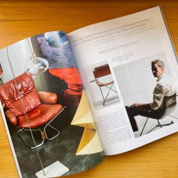 SZOSTAK atelier - Artykuł z magazynu o wnętrzach prezentujący meble i elementy wyposażenia. Widoczny skórzany fotel, lampa i krzesło na metalowym stelażu.