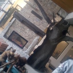 DW-KAM Daniel Wójcik - Wnętrze w trakcie wykańczania: murowany kominek z paleniskiem, atrapa drzewa, rusztowanie. Dekoracja z kunami na pierwszym planie.