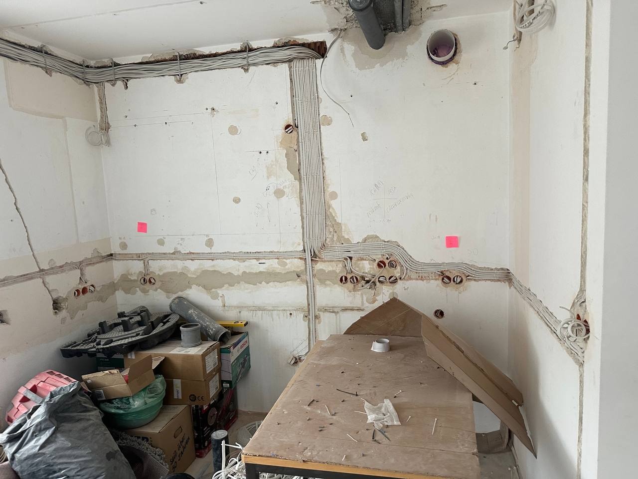 Wnętrze w trakcie remontu: widoczne kable elektryczne prowadzone w bruzdach na ścianach, przygotowane pod gniazdka, zarys instalacji elektrycznej w pomieszczeniu.