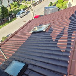 FULMAL Piotr Górka - Częściowo pomalowany dach z dachówki ceramicznej w odcieniach brązu i grafitu, z widocznymi oknami dachowymi i fragmentem ulicy w tle.