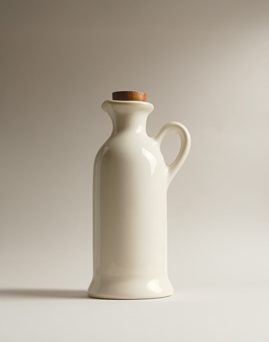 Ceramiczna karafka z drewnianym korkiem, oświetlona miękkim światłem, na jednolitym tle. Minimalistyczny styl, idealna do przechowywania oleju lub octu.